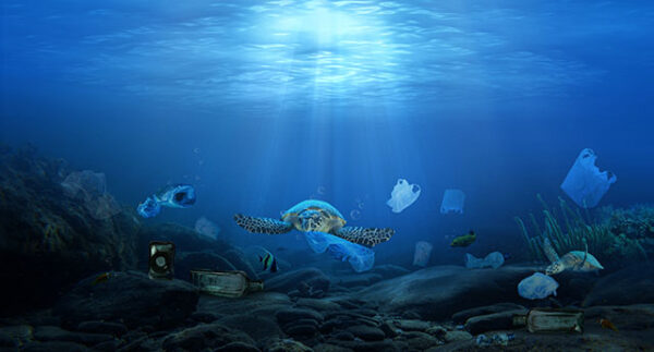 NGC | Underwater scene with a turtle swimming among various types of plastic waste and debris on the ocean floor, with sunlight filtering through the water.