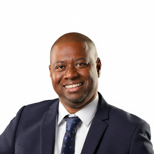 NGC | A member of the Board of Directors in a dark suit, white shirt, and patterned tie smiles at the camera against a plain white background.