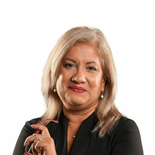 NGC | A woman with shoulder-length blonde hair, wearing a black top and pearl earrings, holds red glasses and looks directly at the camera—capturing the poised confidence of a Board of Directors member against a white background.