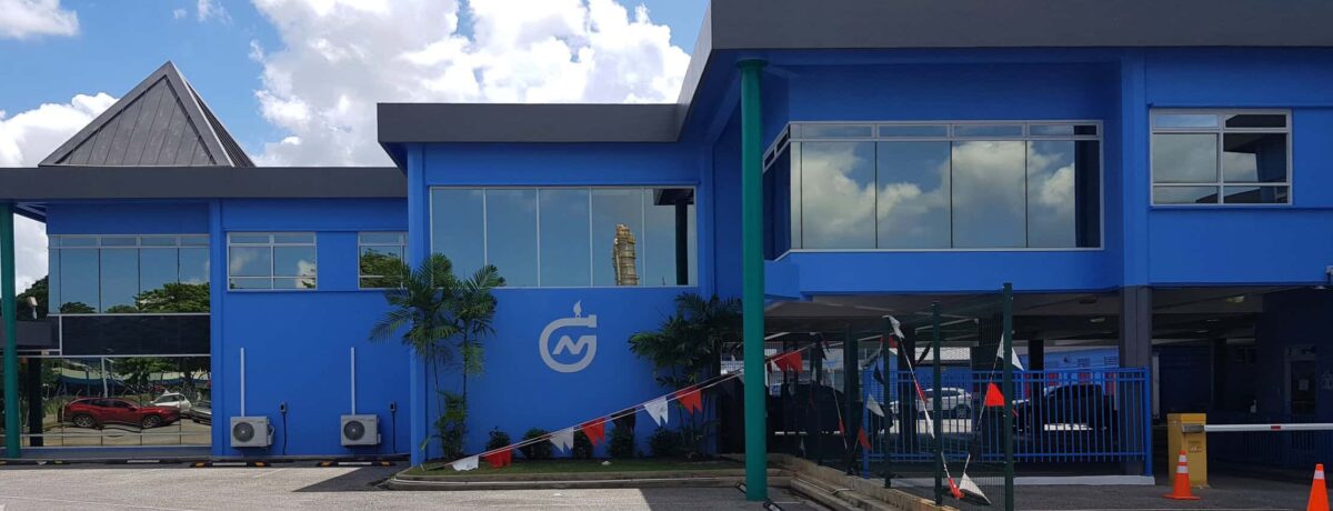 NGC | A modern blue two-story building with large windows, air conditioning units, palm plants, and a logo on the wall reflects strong company leadership under a partly cloudy sky.